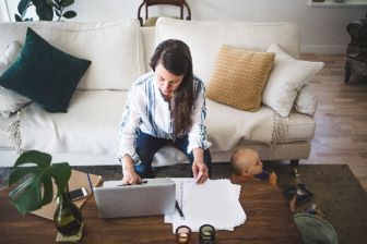 Woman on couch with laptop and papers
